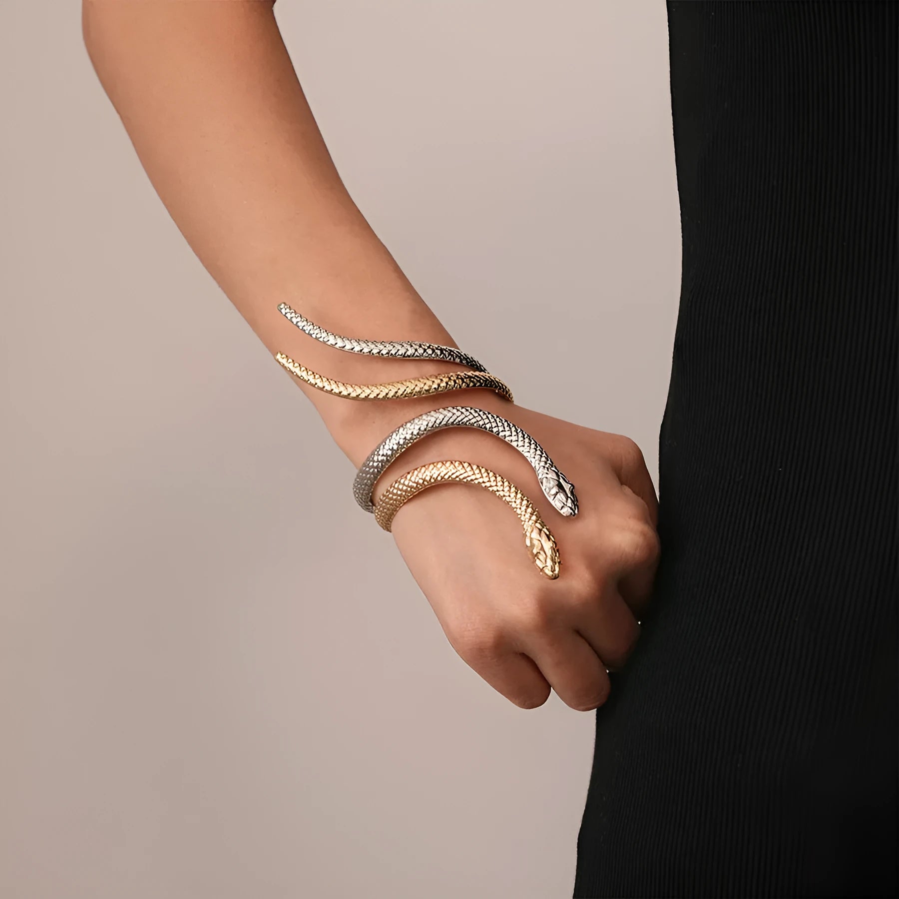 Gold twisted snake design metal bracelet and ring set on a white background.
