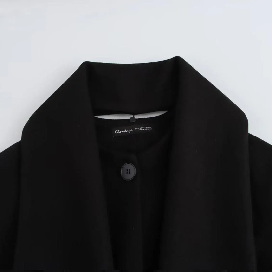 Women's long black polyester coat with a faux fur collar, shown in a street fashion style.
