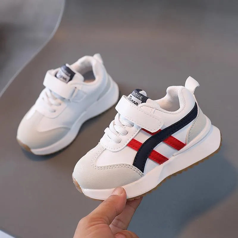 Children's white synthetic leather sneaker with a single Velcro strap and rubber sole.