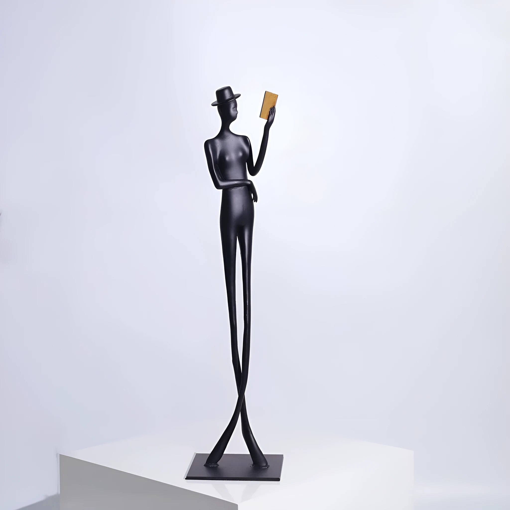 Black cast aluminium sculpture of a woman reading, modern minimalist style.