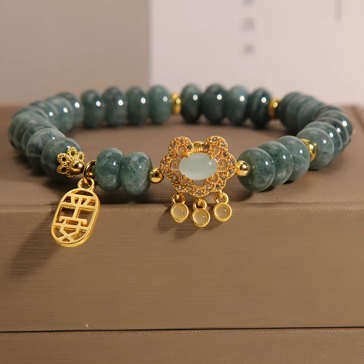 Close-up of a women's bracelet with green emerald jade abacus beads and a silver-toned alloy safety lock clasp.