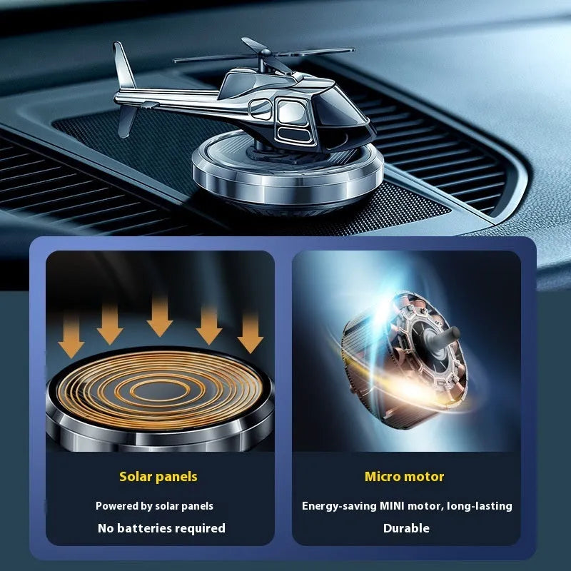 Silver solar-powered metal helicopter car air freshener ornament with rotating blades on a dashboard.
