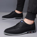 Men's black leather-toe casual shoes with a fabric upper and rubber sole on a plain background.