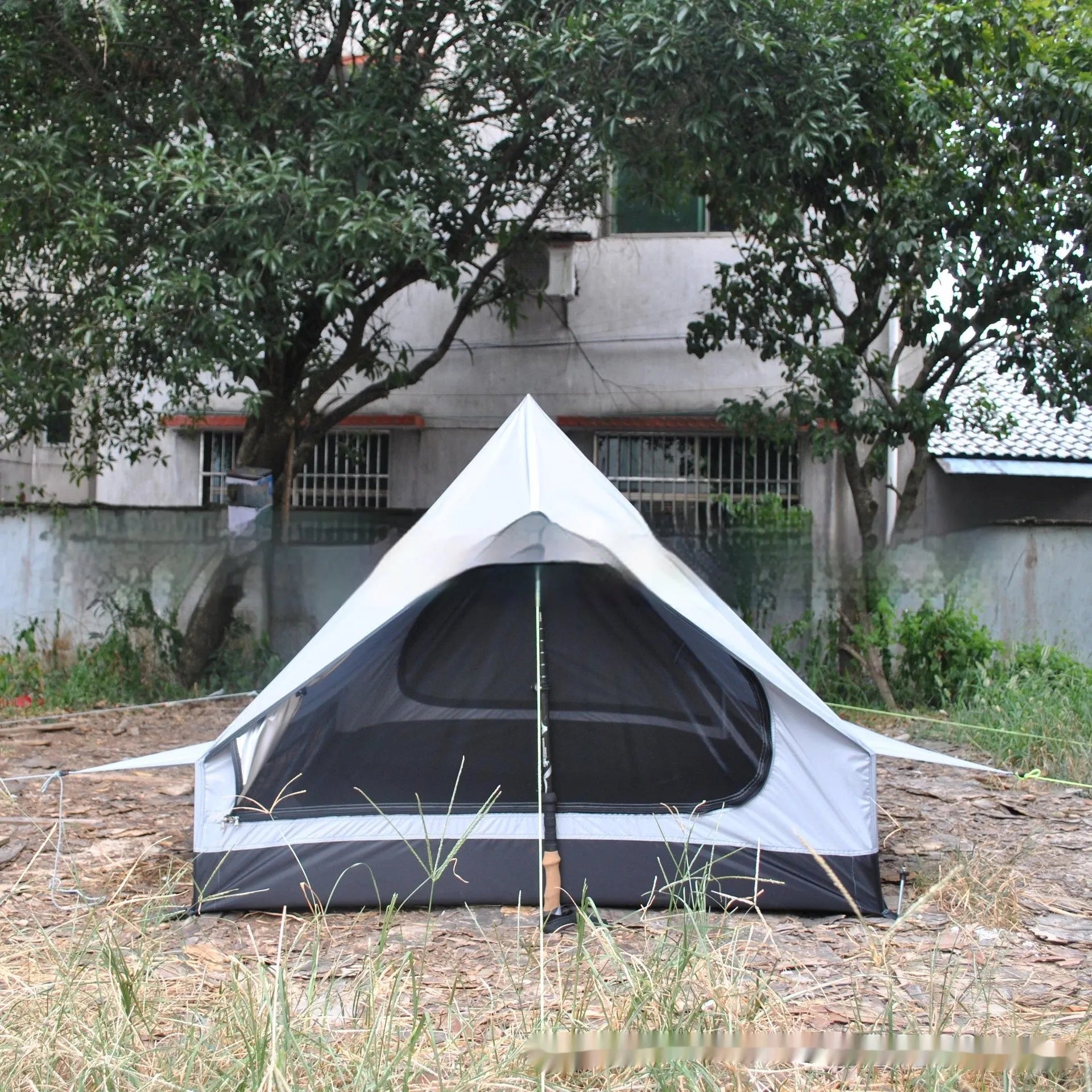 Brown and white pole-free A-line cabin tent set up with hiking canes, showing spacious interior