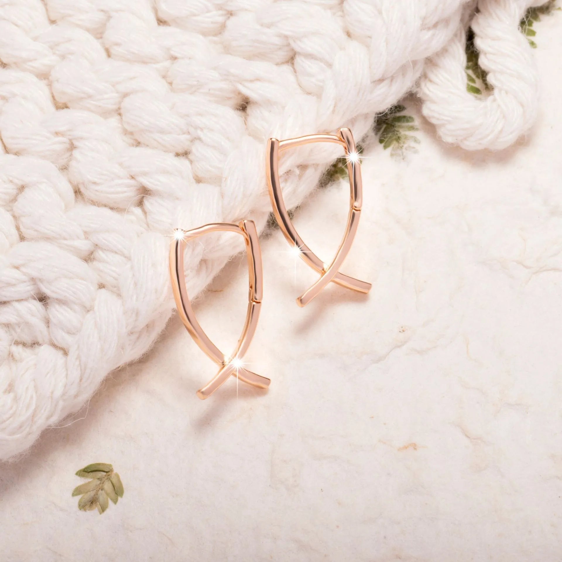 Rose gold cross shaped earrings with copper construction and light luxury aesthetic