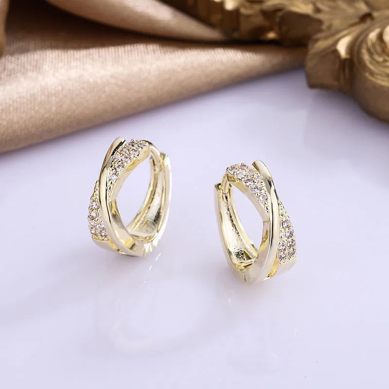 A pair of geometric stud earrings with zircon detail and 14K yellow gold plating on a copper base.