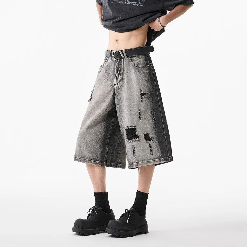 Grey women's denim shorts with distressed hole details and a loose, cropped fit
