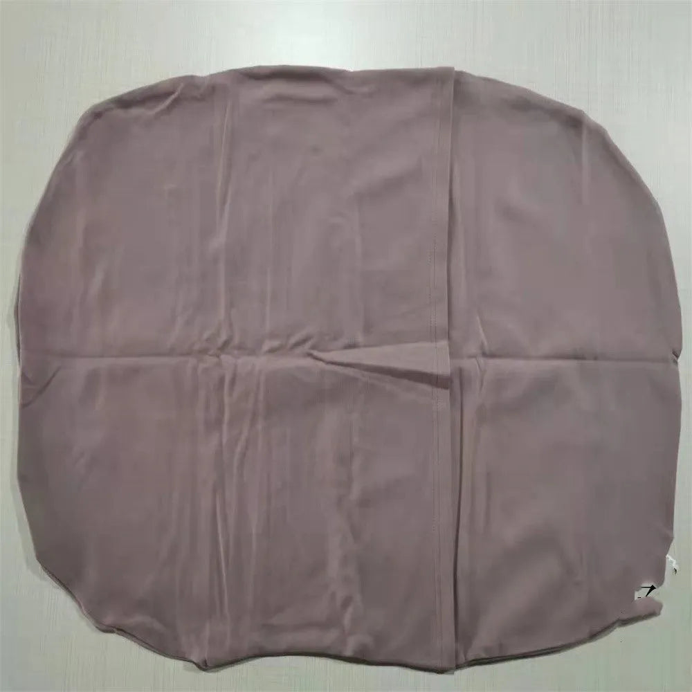 Beige portable cotton baby nest crib for newborn infants on a bed.