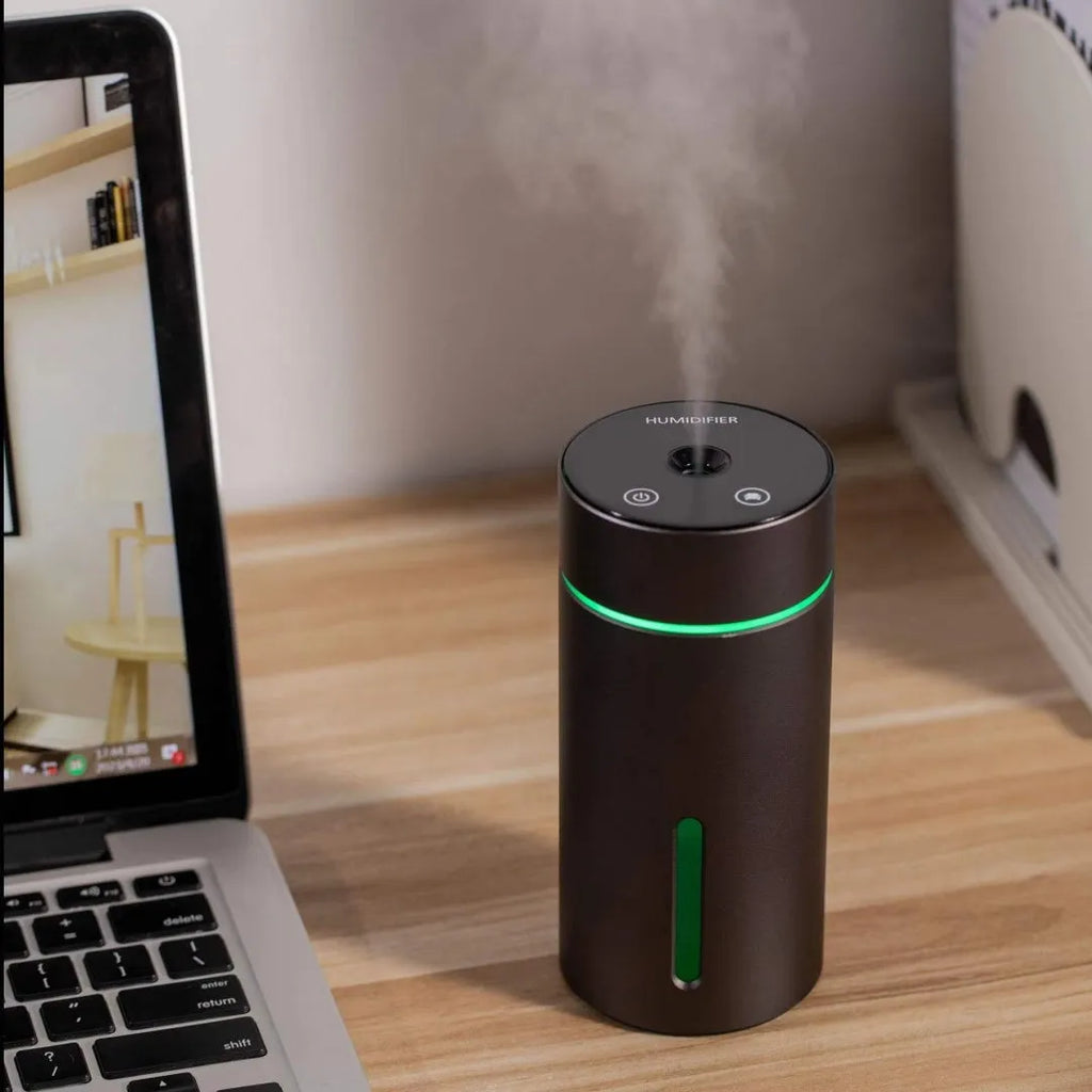 Compact aluminium car humidifier and essential oil diffuser with night light on a desk.