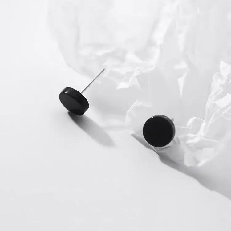 A pair of round, flat S999 sterling silver bone stud earrings on a plain background.