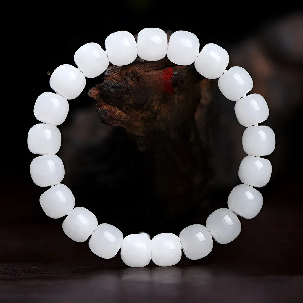 White Hetian jade barrel bead bracelet on a wrist, showing the traditional bead design.