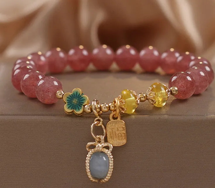 Red strawberry quartz beaded bracelet with silver-toned alloy charms and clear rhinestone details.