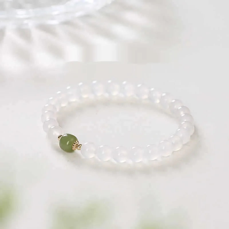 Handmade white agate bracelet with red cinnabar letter inlays on a wrist.