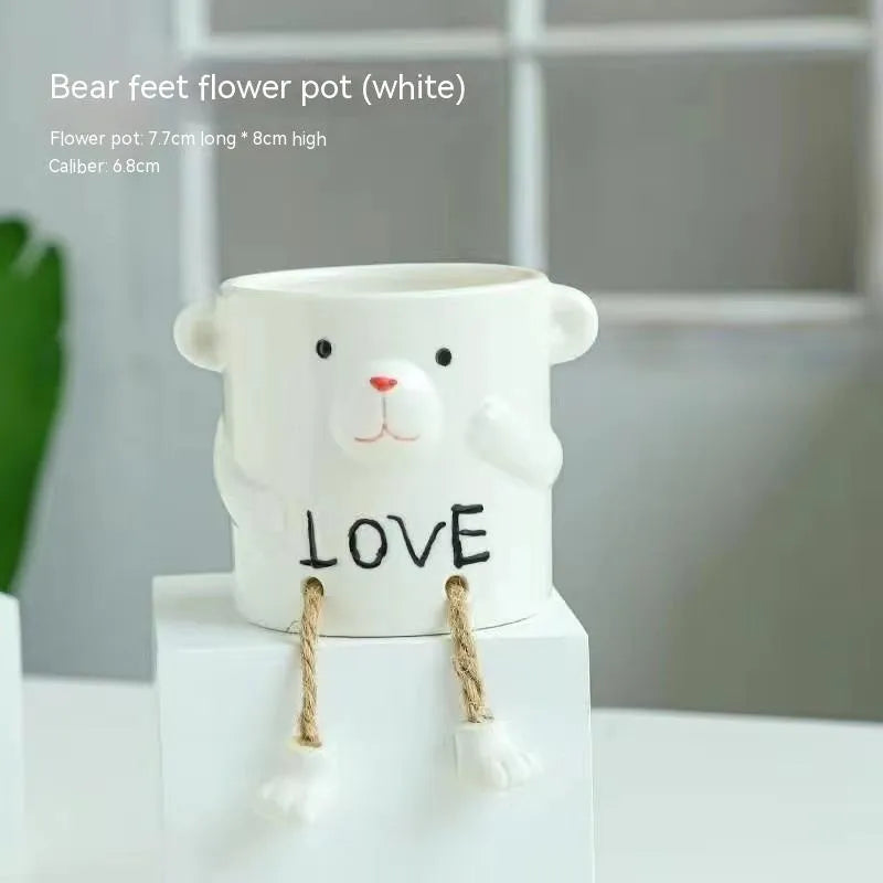 Ceramic cartoon-style hanging foot flowerpot for succulent plants on a desktop.
