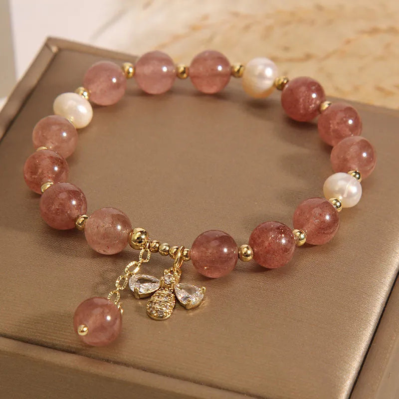 Close-up of a women's bracelet with pink strawberry quartz stones, white freshwater pearls, and sparkling zircon accents on an alloy clasp.