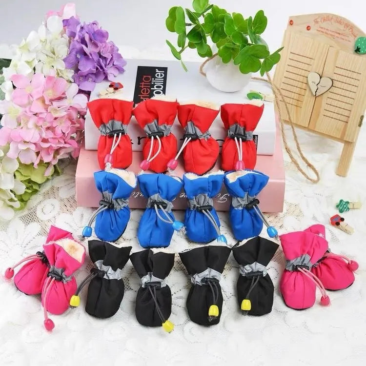 Set of four cloth dog shoes with soft soles in assorted colours on a neutral background