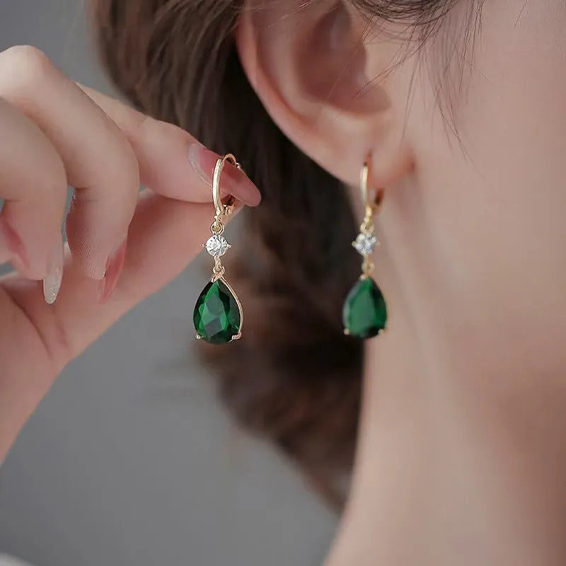 A pair of green geometric teardrop-shaped alloy earrings on a plain background.