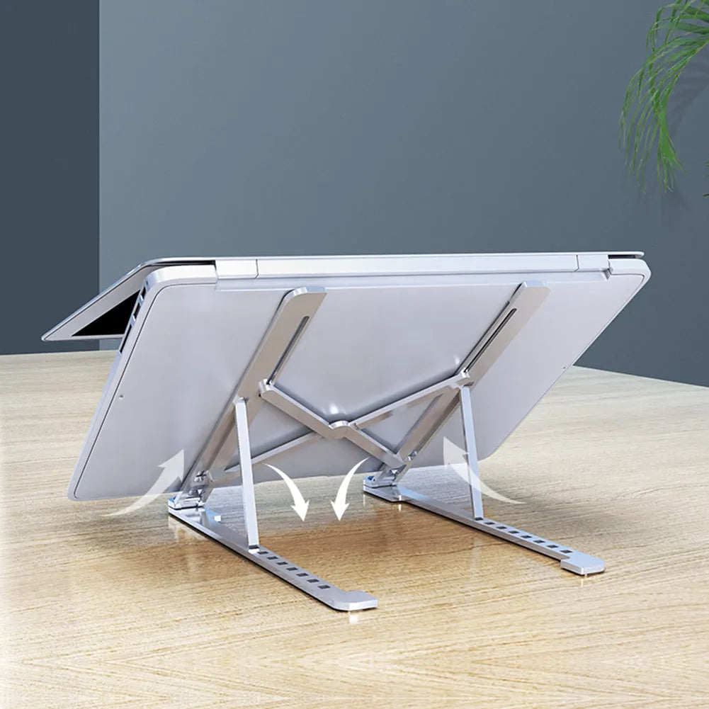 Aluminium laptop stand in silver, folded flat next to an open laptop showing its adjustable height mechanism.
