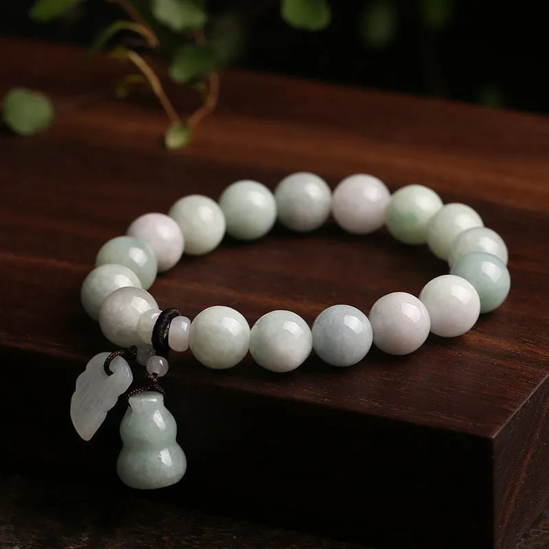 Natural green jade bracelet with a geometric hanging pendant showing choice of symbolic designs.