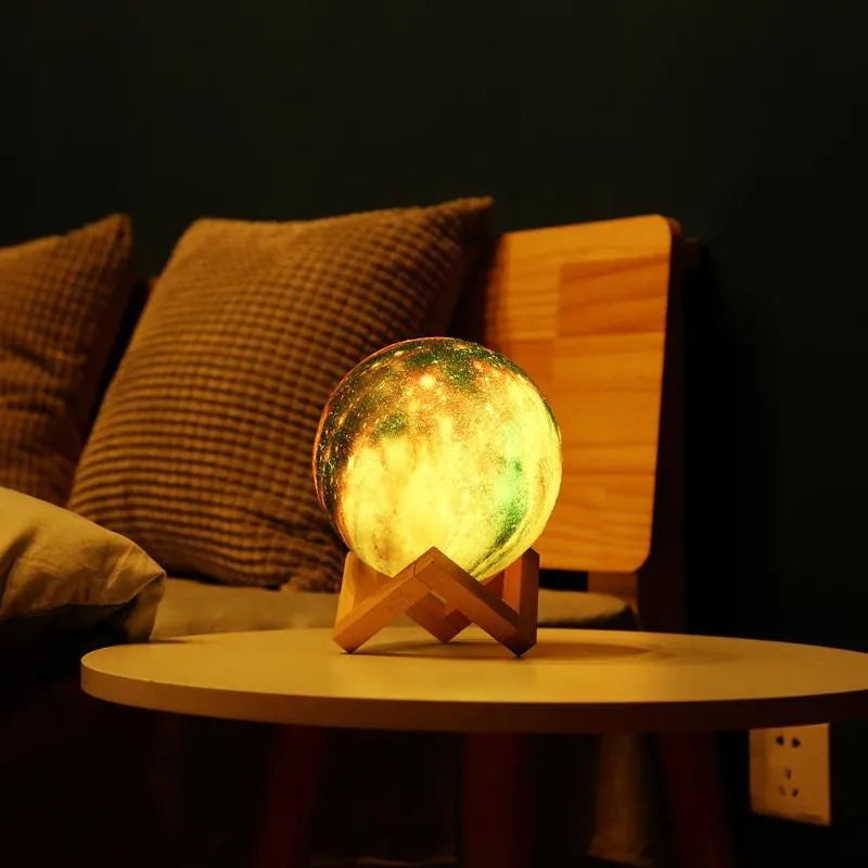 White 3D-printed moon lamp on a table showing crater details, with a remote control beside it.