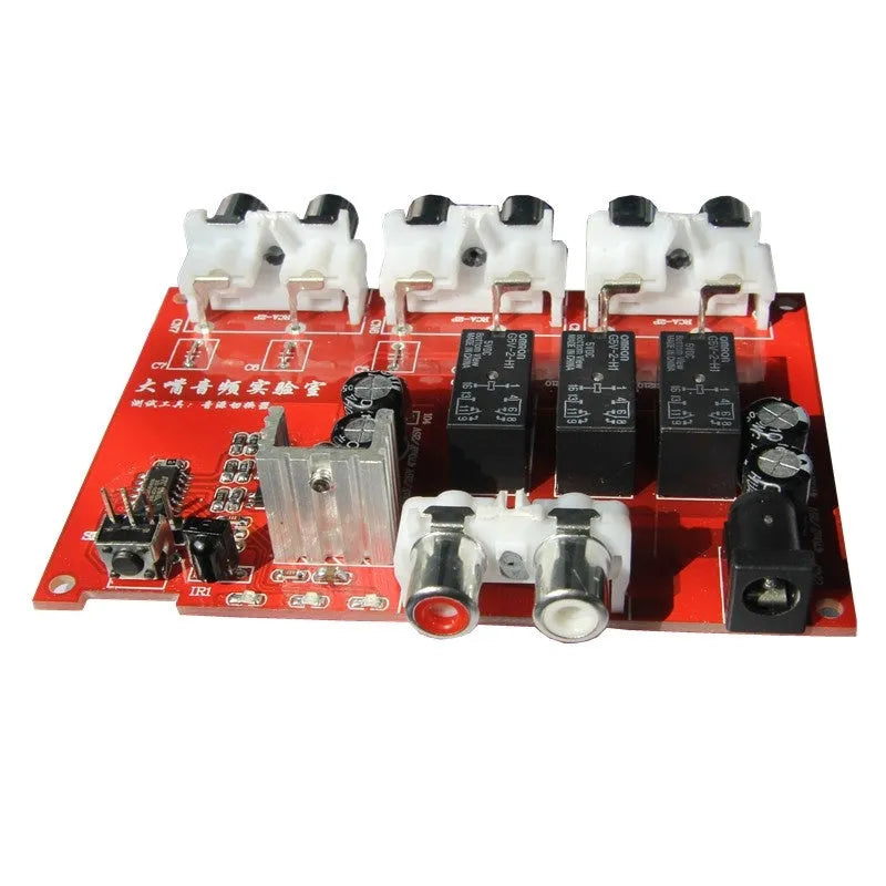 Silver aluminium audio source selector switch with infrared remote control on a shelf.