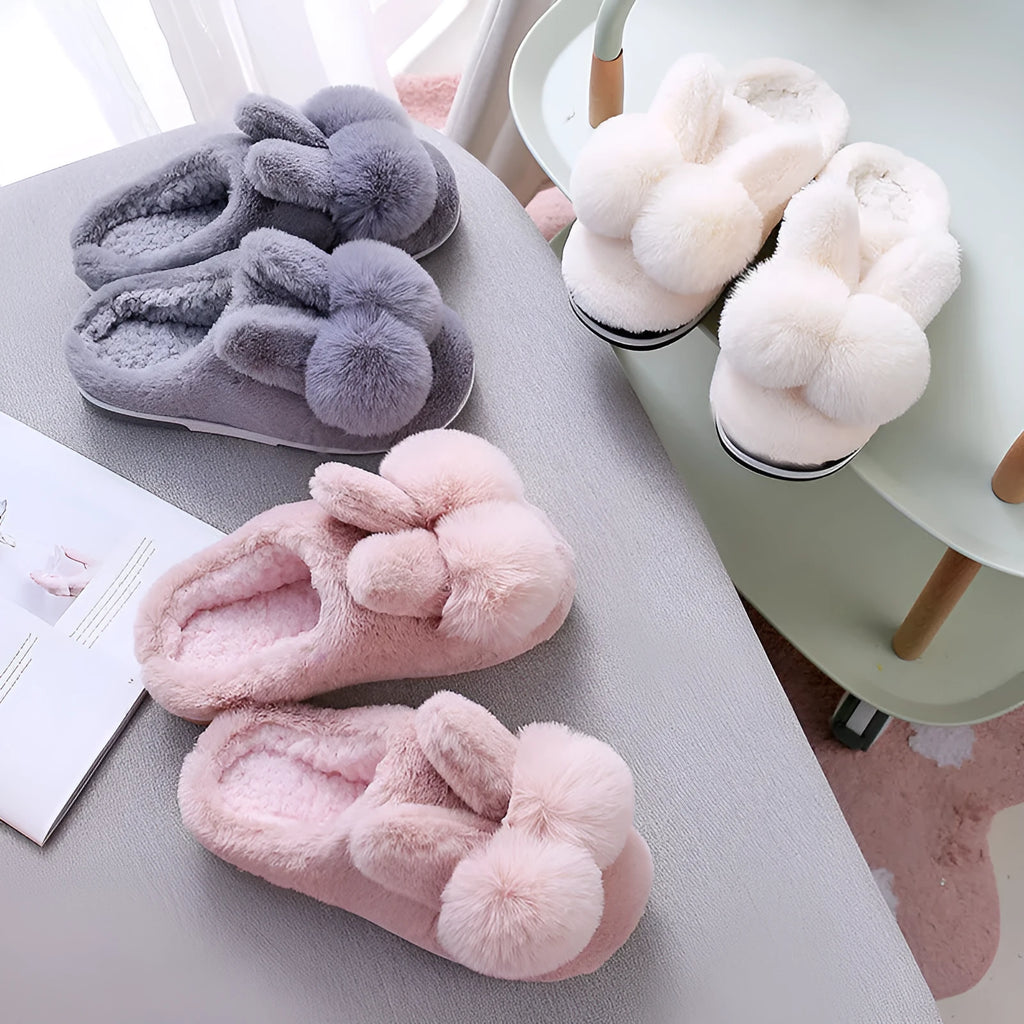 Women's fluffy bunny slippers with rabbit fur upper in cream colour on a wooden floor.