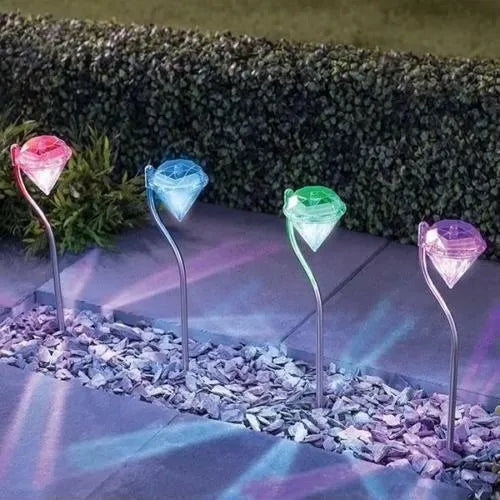 White solar-powered LED garden spotlight with adjustable angle and solar panel on a stake.