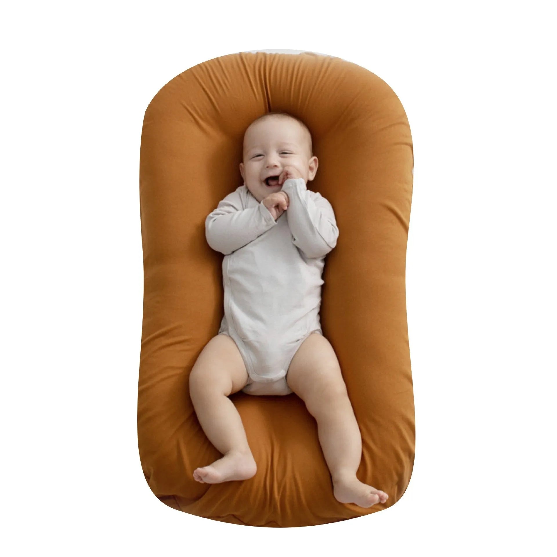 Beige portable cotton baby nest crib for newborn infants on a bed.