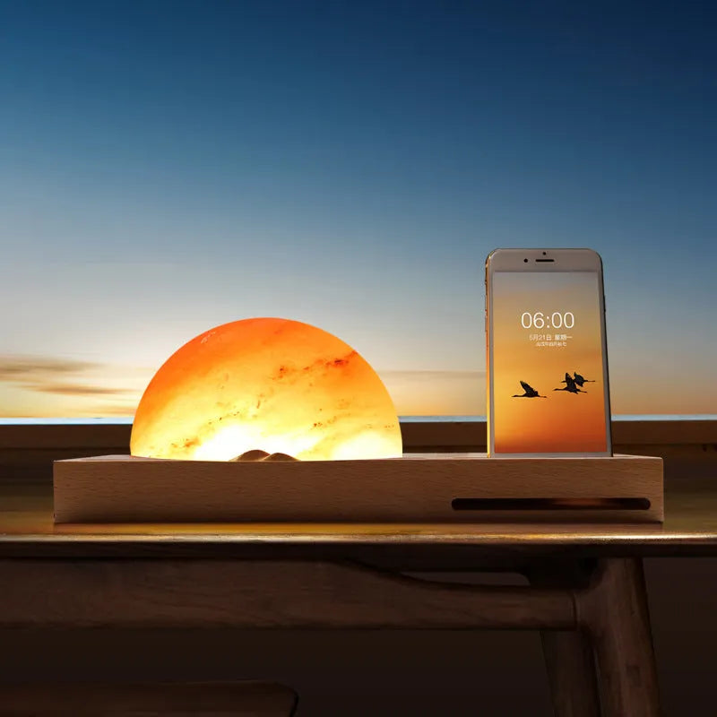 Natural crystal salt lamp with wireless charging pad on a light beech wood table base.