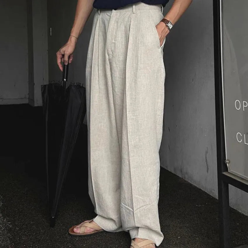 Men's apricot coloured loose-fit cotton linen blend trousers on a hanger, showing zip fly and mid-waist design.