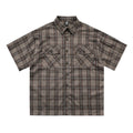 Man wearing a brown plaid short sleeve shirt with embroidery on the lapel