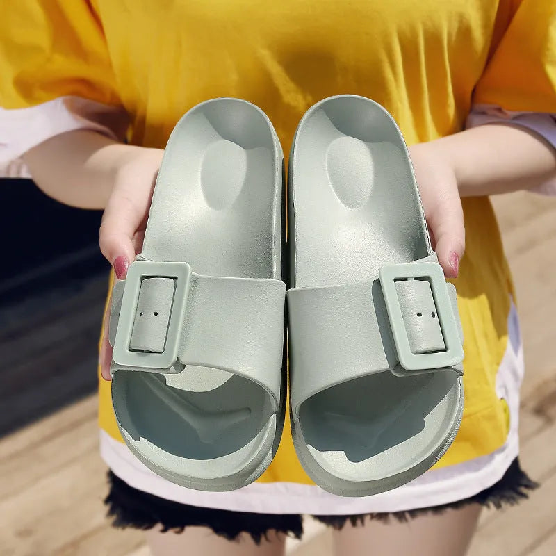 Women's grey blue flip flop slippers with a silver buckle on the strap and a textured EVA sole.