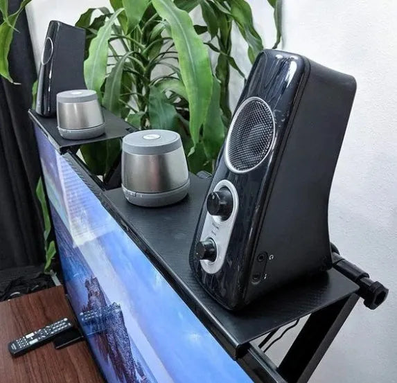 Black adjustable 13-inch screen top shelf mounted above a monitor, holding a streaming device and remote.
