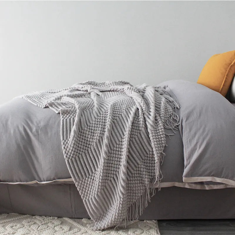 Small grey polyester nap blanket measuring 127 by 170 centimetres folded on sofa
