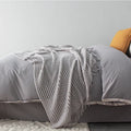 Small grey polyester nap blanket measuring 127 by 170 centimetres folded on sofa