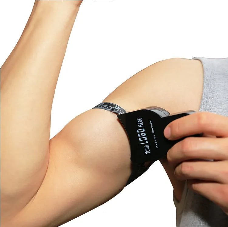 Black ABS plastic body fat caliper with measurement scale and a retractable measuring tape.