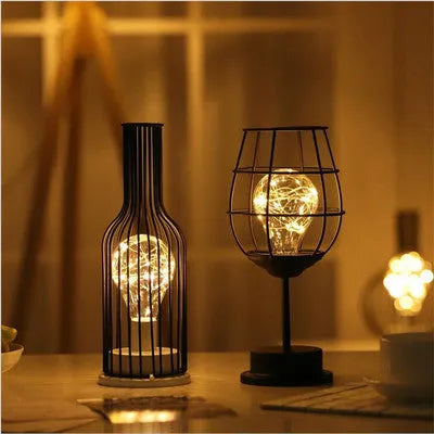 Minimalist wrought iron hollow table lamp in red wine glass style with warm white glow.