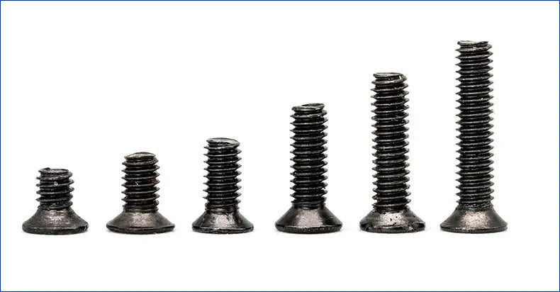 Black countersunk head machine screws for laptop repair, shown in a pile next to a box.