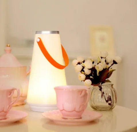 White rechargeable LED bedside lantern with warm light, shown next to a USB charging cable.