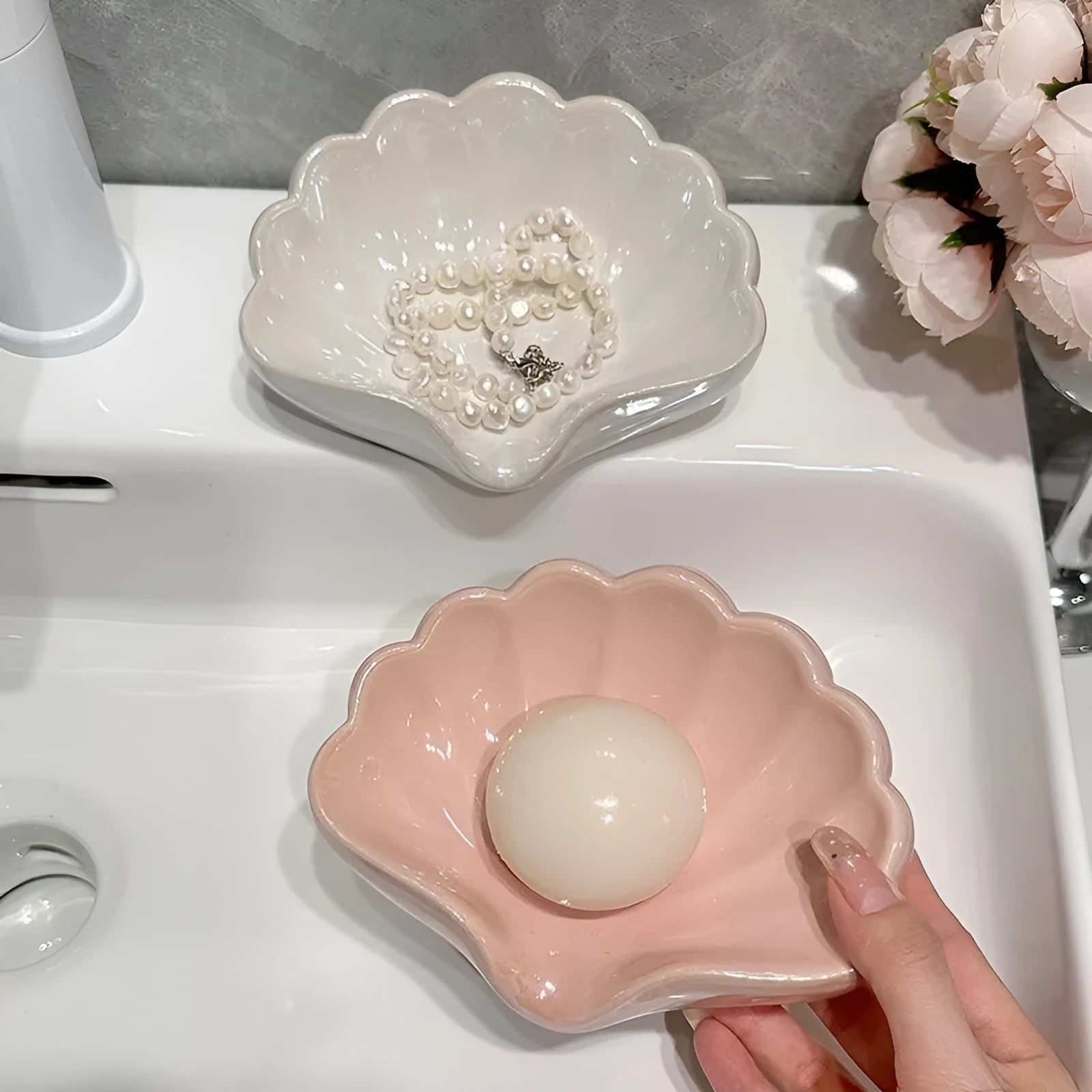 White and pink plastic shell-shaped soap dish for bathroom countertops.