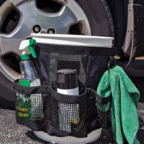 Black cylindrical polyester storage bag hanging on a 5-gallon water barrel for organising tools and gear.