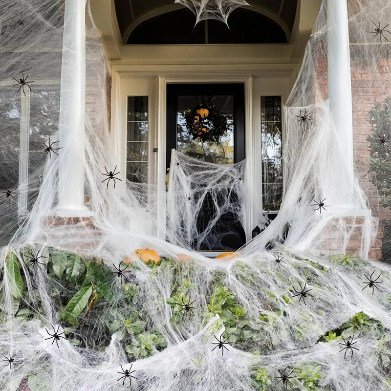 White cotton Halloween spider web decoration with plastic spiders on dark background