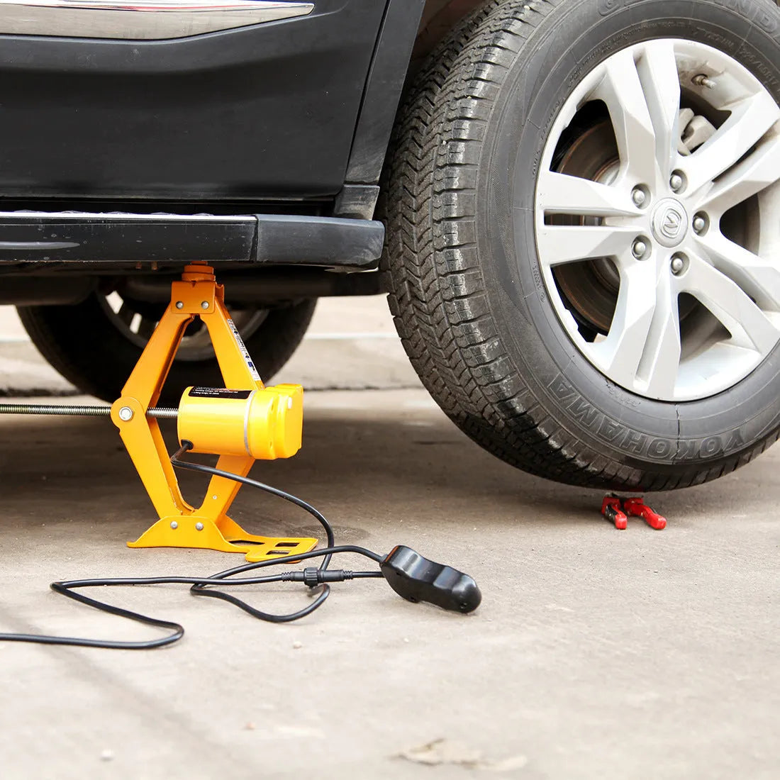Electric hydraulic car jack kit with 2 tonne lifting capacity mounted in a vehicle boot.