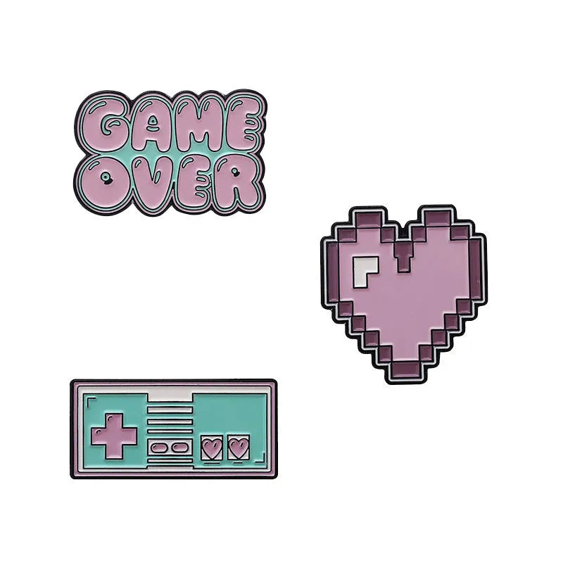 A metal alloy game console badge shown in one of three available colours, suitable for attaching to bags.
