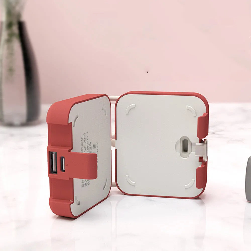 Handbag clip-on power bank in blue showing USB-A and Type-C ports, with phone propped in its integrated stand.
