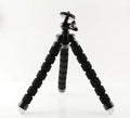 Black mini flexible octopus tripod with wrapped legs next to a smartphone.