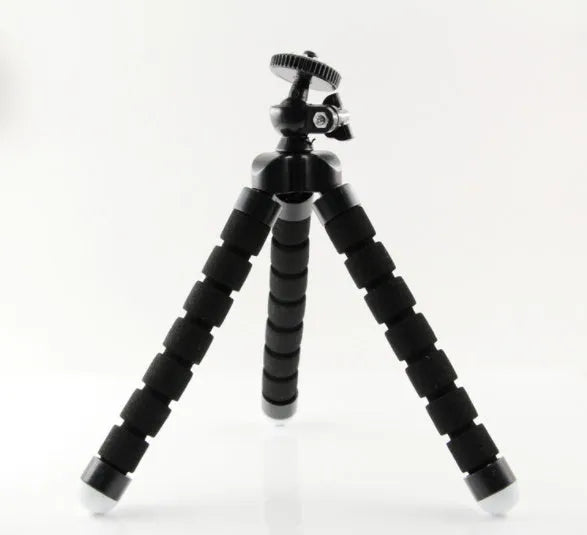 Black mini flexible octopus tripod with wrapped legs next to a smartphone.