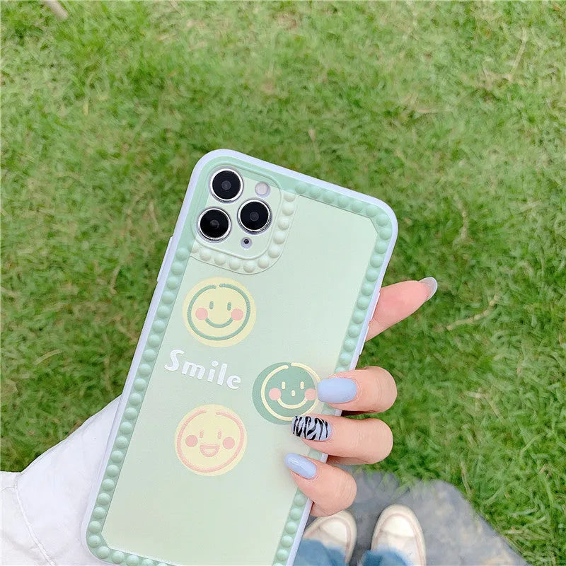Green TPU iPhone case with geometric smiley face and polka dot design on a simple back cover.