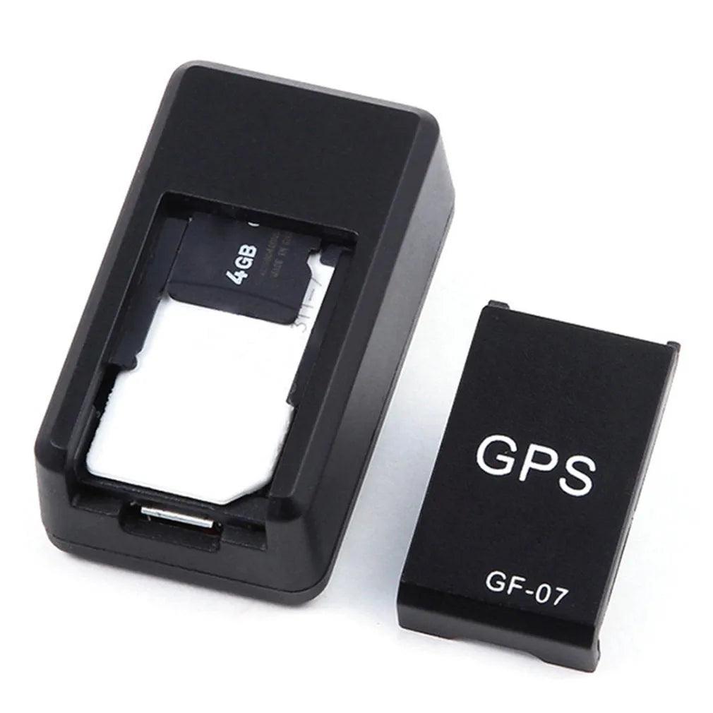 Black mini magnetic GPS tracker next to USB charging cable on a dark surface.