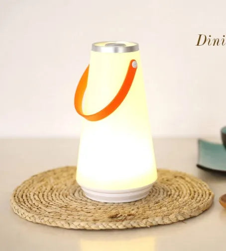 White rechargeable LED bedside lantern with warm light, shown next to a USB charging cable.